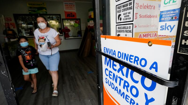ARCHIVO - Una mujer sale de una tienda que ofrece servicios para enviar remesas a México y...