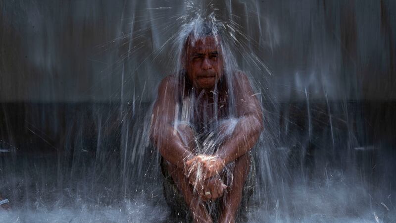 Un hombre se refresca bajo una fuente de agua en el Parque Madureira en medio de una ola de...