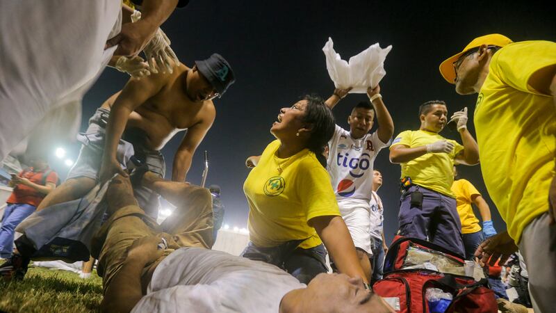 Aficionados al fútbol atienden en la cancha a los heridos por una estampida humana en el...